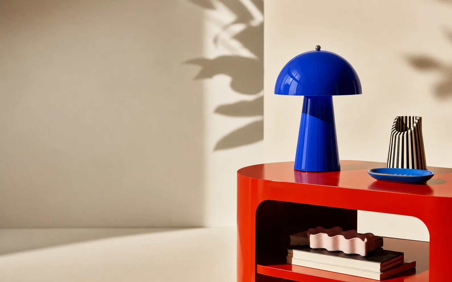 Grafische blauwe designlamp op een rode bijzettafel